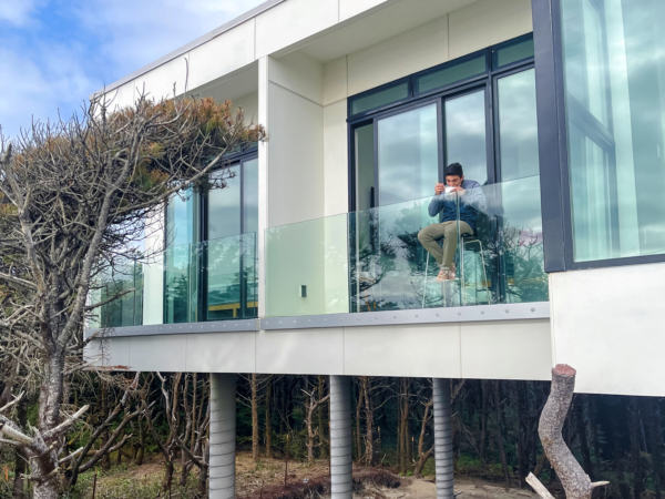 Glass railing customer enjoying breakfast on their deck overlooking the beach