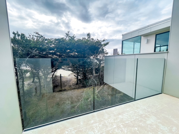 Base shoe glass railing on balcony overlooking the path to the beach