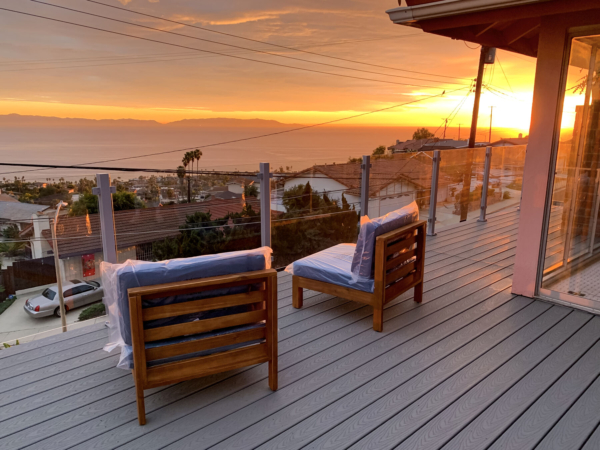 New lounge chairs being set up on a freshly completed deck with glass railing